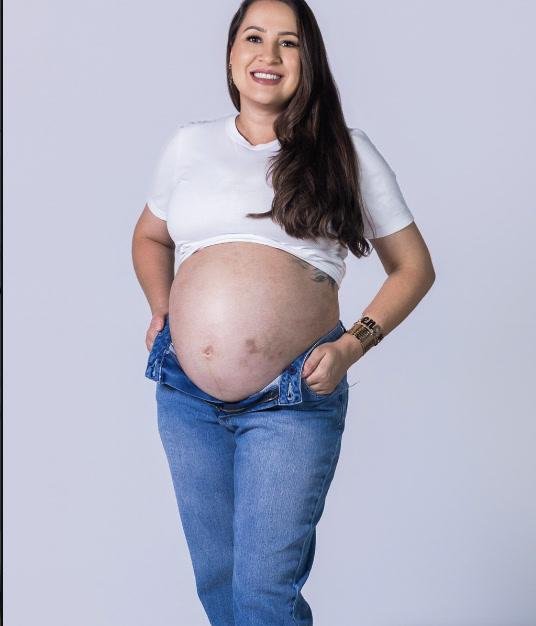 Ana grávida, de camiseta branca e jeans